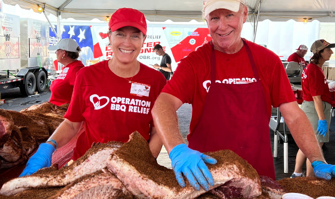 Volunteers in red shirts serving barbecue at a community event.