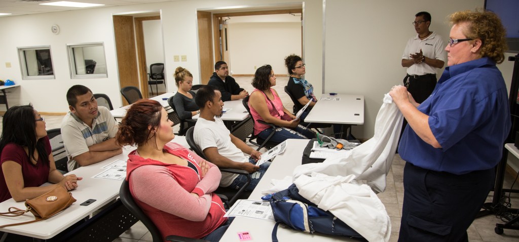 Instructor demonstrating protective clothing to a classroom of employees during training.