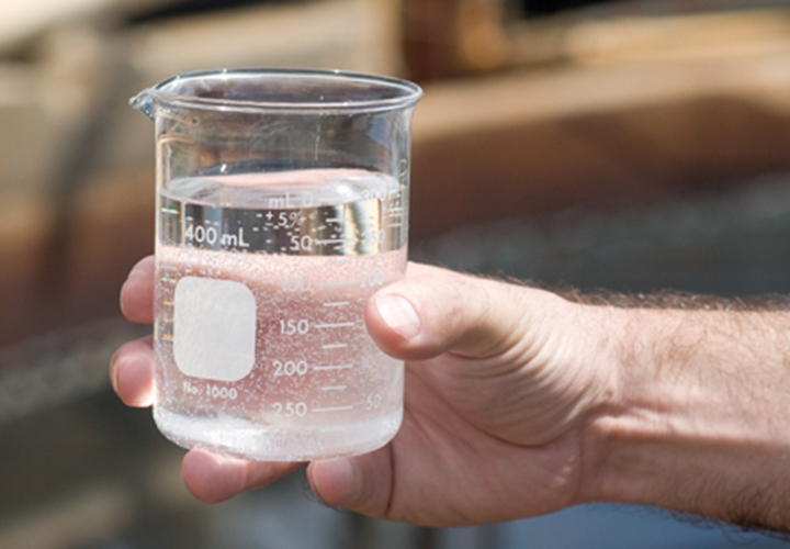 Hand holding a clear beaker filled with water.