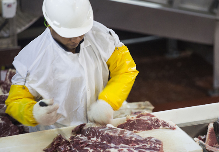 An employee trimming beef on the processing line.