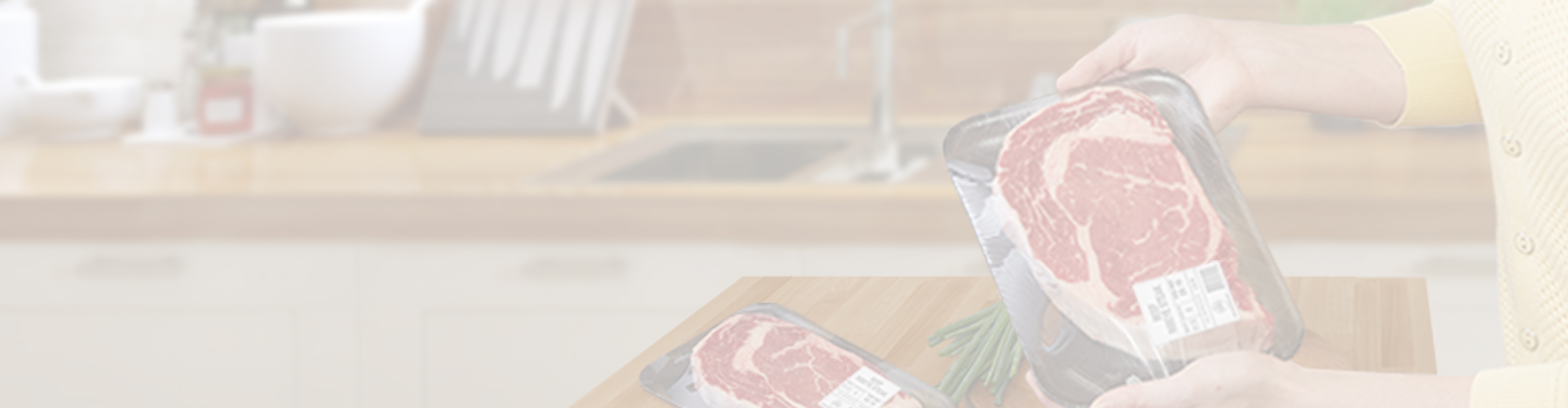 Person holding a packaged steak while another packaged steak sits on a kitchen counter.