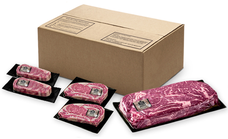Box of vacuum-sealed beef cuts with several individually packaged steaks arranged in front.
