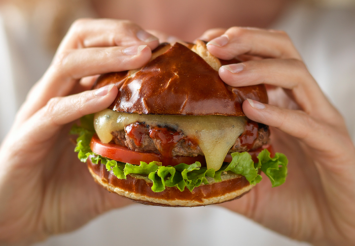 A person holding a burger with a soft white fade.