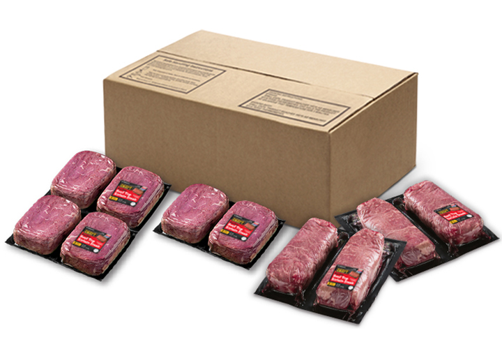 Vacuum-sealed multi-pack steaks arranged in front of a cardboard shipping box.