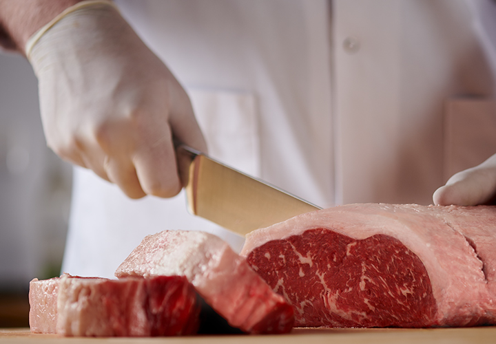 A butcher slicing steak.