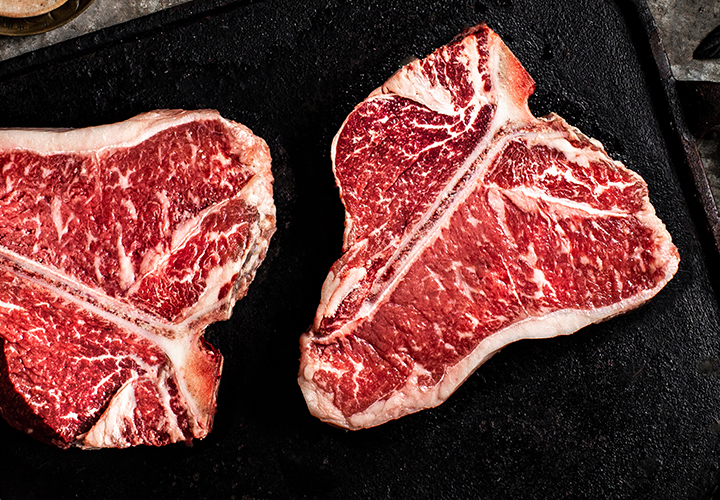 Raw T-bone steak on a dark griddle surface