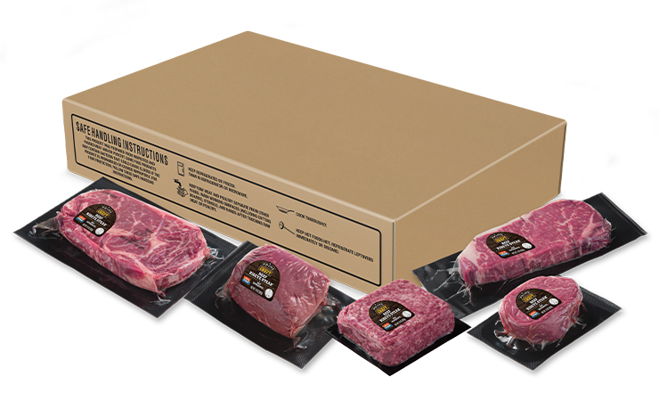 Box of vacuum-sealed prime beef cuts with several individually packaged steaks arranged in front.