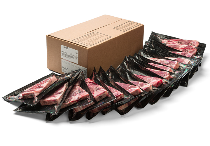 Row of vacuum-sealed sliced beef cuts arranged in front of a cardboard shipping box.