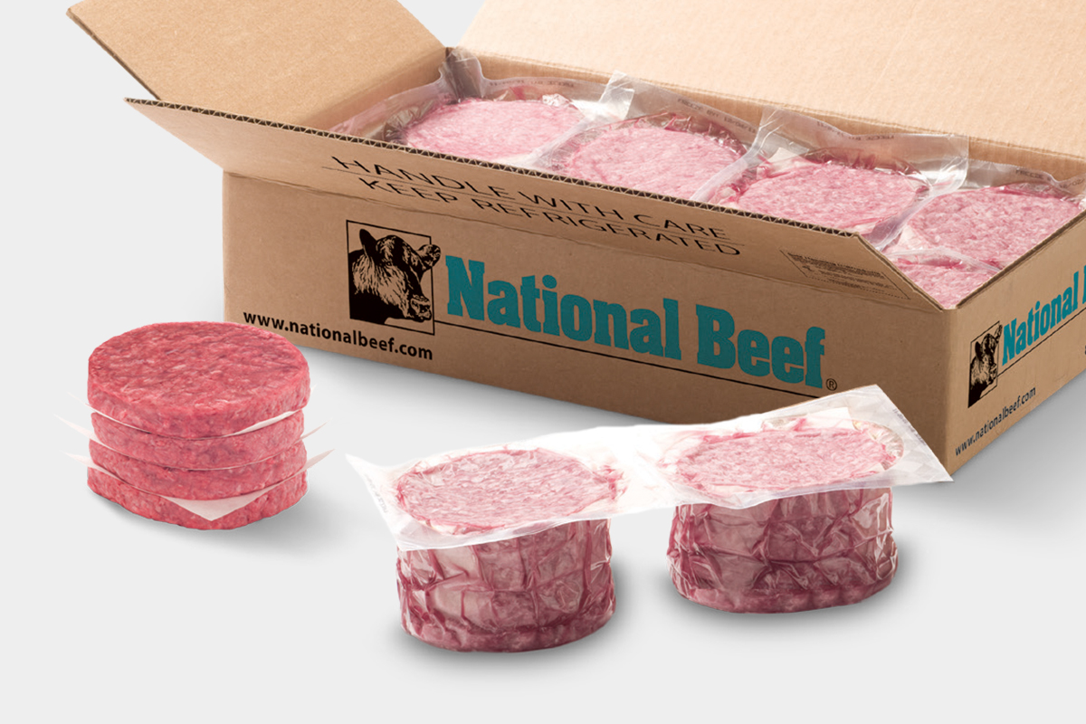 Open National Beef case with vacuum-packed raw beef patties stacked inside and two packs in front