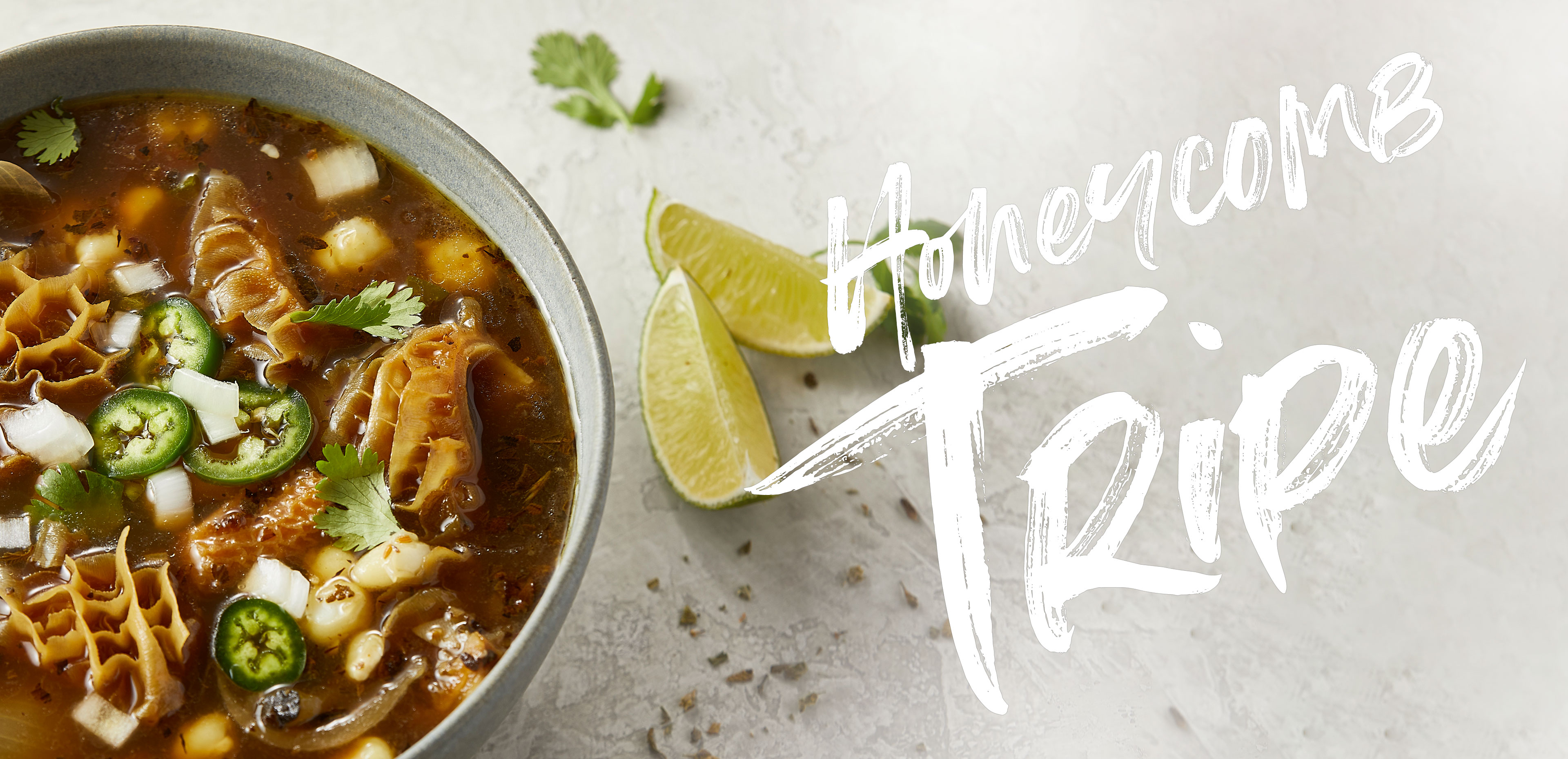 Overhead view of tripe soup with onions, jalapeños, and cilantro.