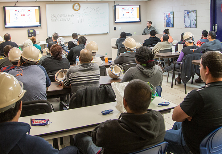 Workers wearing hard hats attending a safety or training presentation.