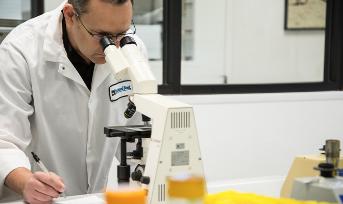 Lab technician examining a sample through a microscope.