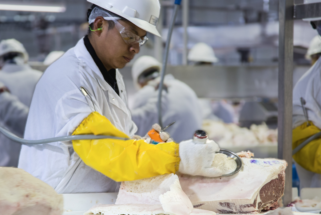 Worker trimming beef in a processing facility.