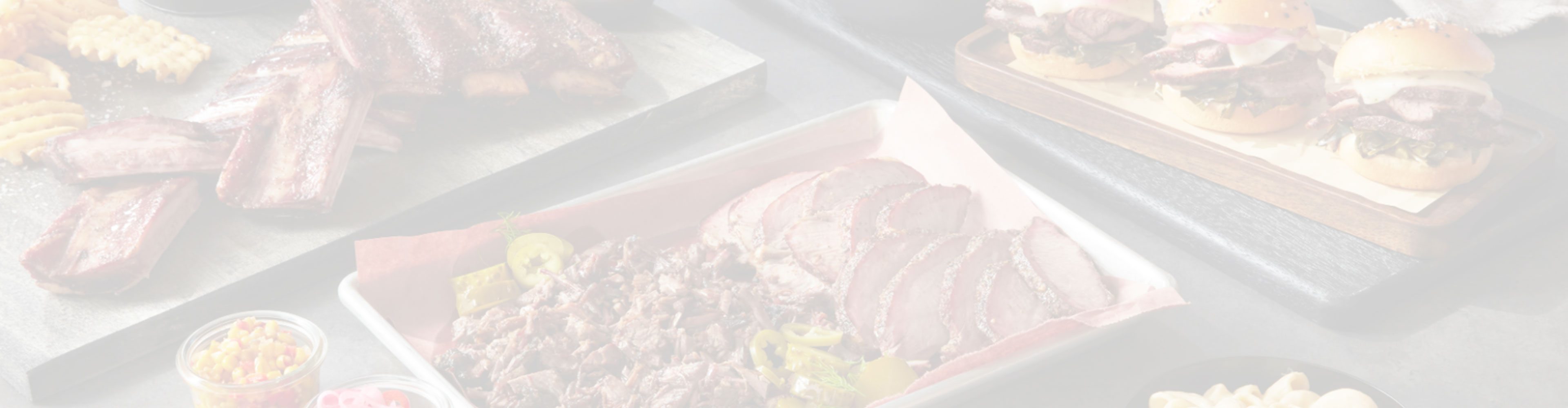 Light overlay image showing assorted cooked meats and sides.