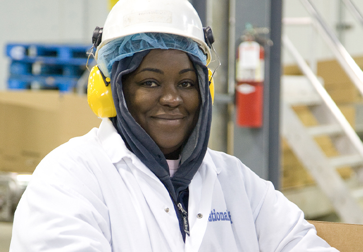Industrial worker in safety gear standing near machinery.