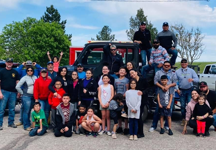 Large group of families and friends posing outdoors in front of a truck.