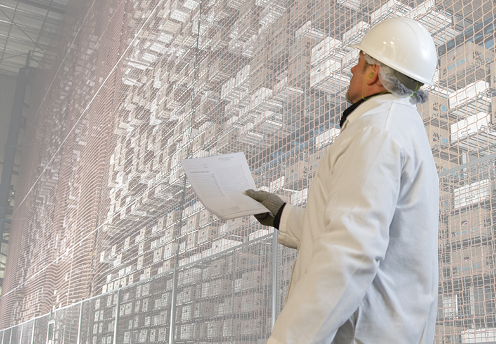 Worker in hard hat reviewing documents in a facility.
