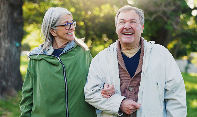 Senior couple hiking outdoors with mountains in the background.