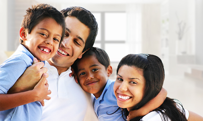 Parents with two young children smiling together.