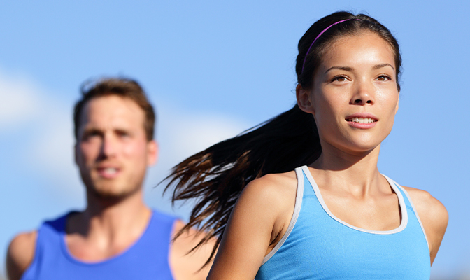 Man and woman jogging outside on a sunny day.