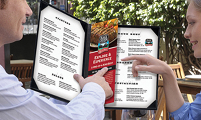 Two people reviewing a steakhouse menu together.