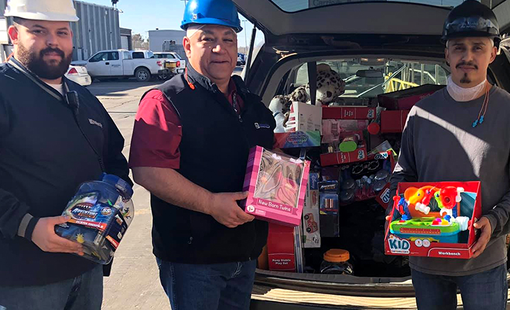 Workers in hard hats collecting toys from a vehicle for donation.