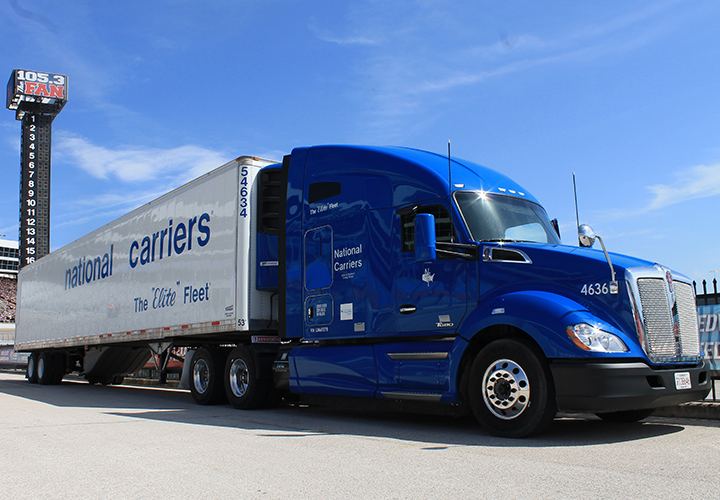 Blue semi-truck labeled “National Carriers” parked outdoors.