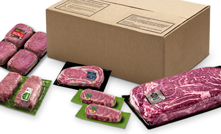 Assorted packaged cuts of beef displayed in front of a plain shipping box.