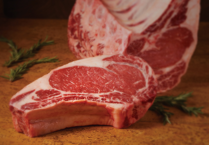 Raw ribeye steak with sprig of rosemary