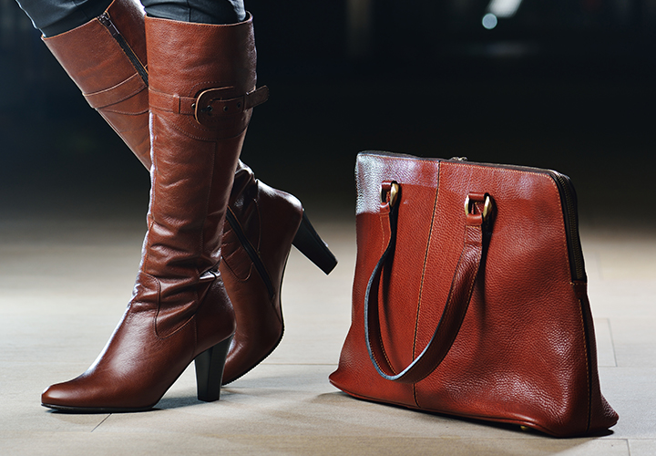 Brown leather high-heeled boots and matching handbag on a light background.