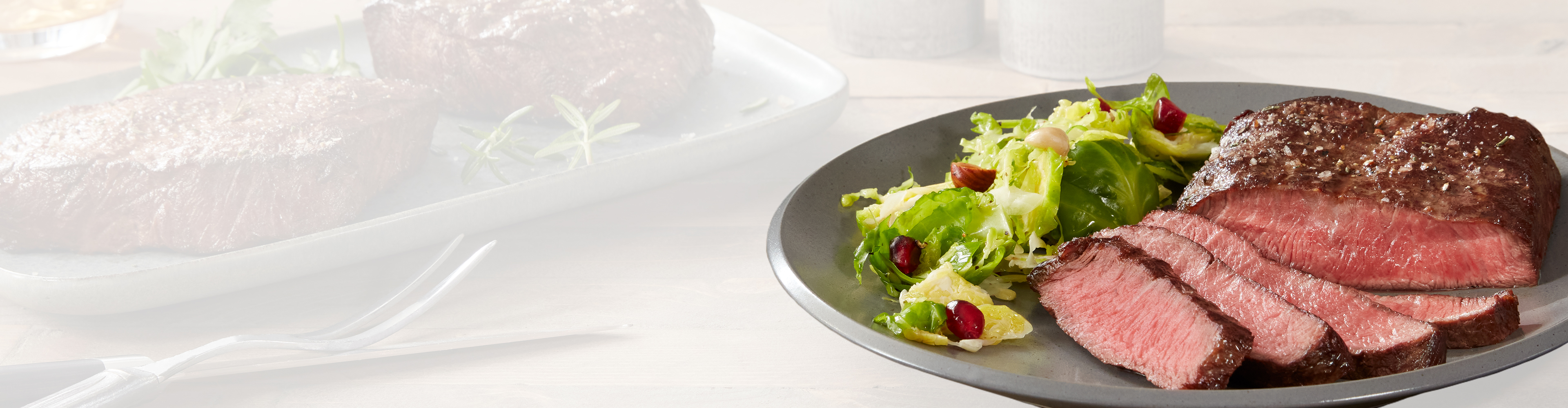 Flat Iron steak on a silver plate with a small side salad.