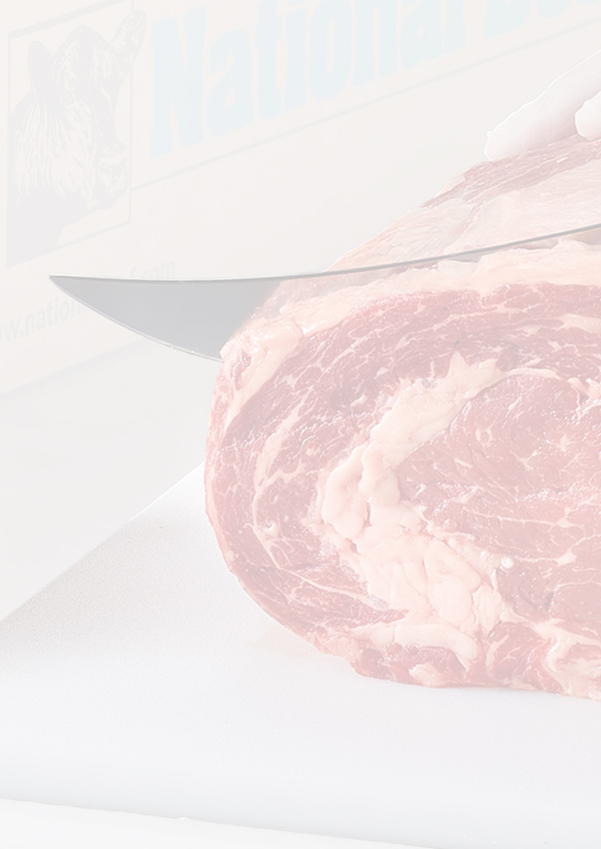 Person slicing a large ribeye roast beside stacked beef patties and a National Beef box.