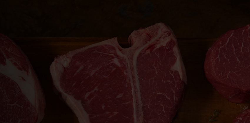 Variety of raw steak cuts arranged in a row on a wooden board
