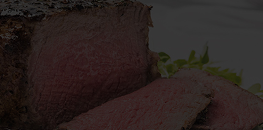 Sliced beef served on a white plate with herbs.