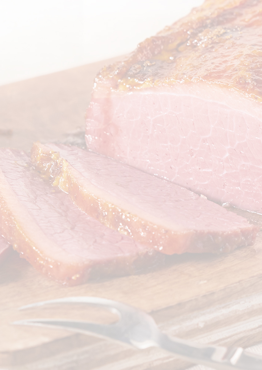 Sliced corned beef on a cutting board with a small bowl of mustard sauce.