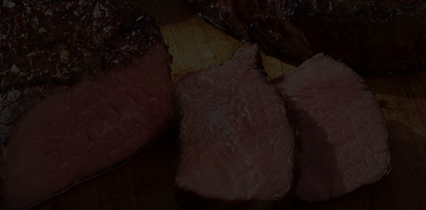 Sliced medium-rare beef on a wooden cutting board