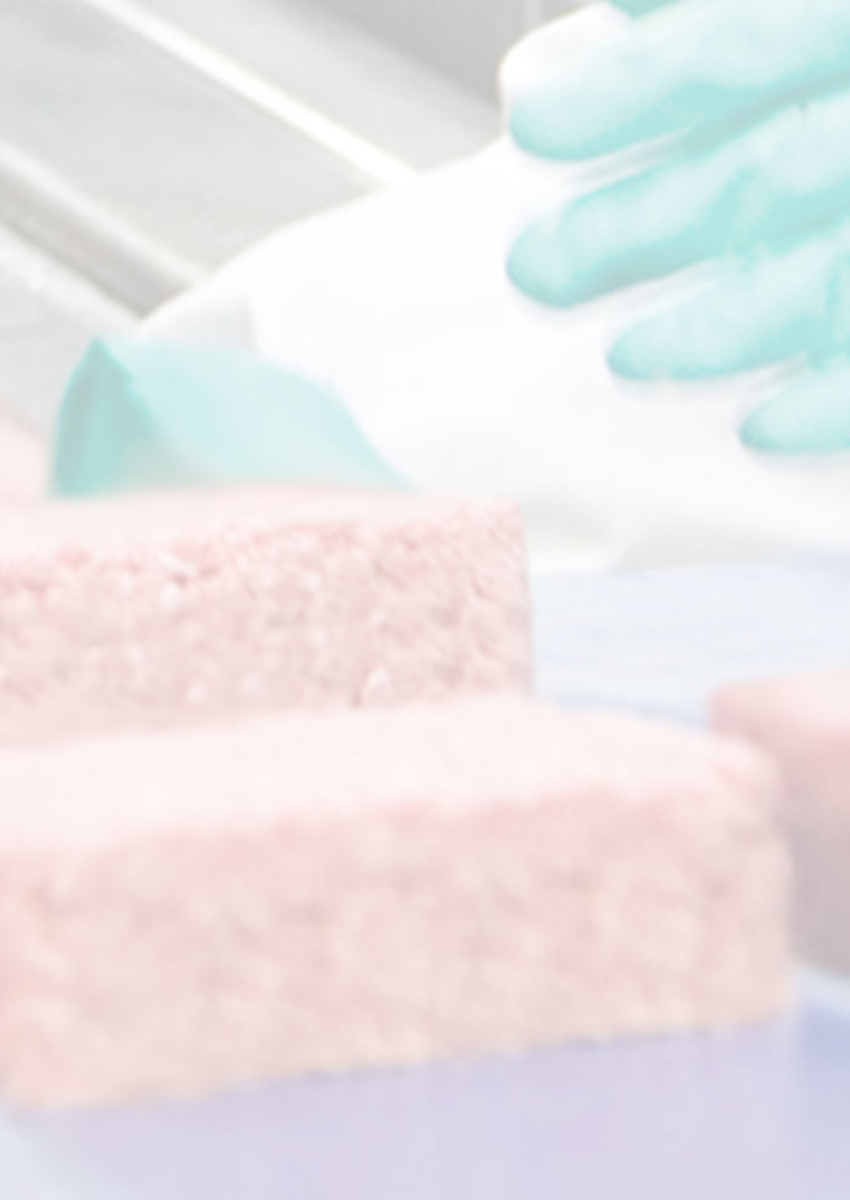 Workers wearing gloves handling square portions of ground beef on a processing line.