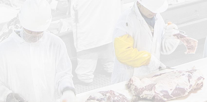 Workers trimming and sorting meat at processing table.