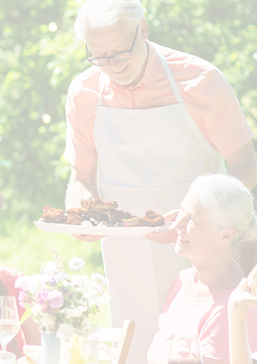 Family enjoying an outdoor meal at a sunny picnic table surrounded by greenery.