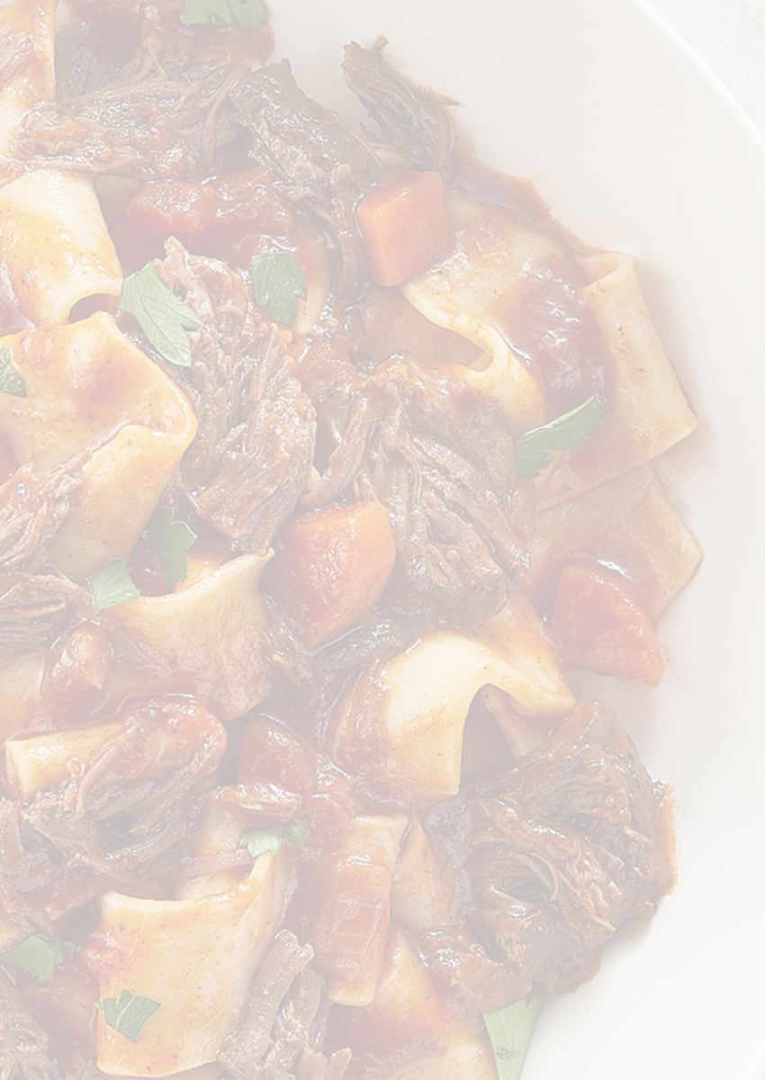 Bowl of pasta with shredded beef and tomato sauce garnished with herbs.